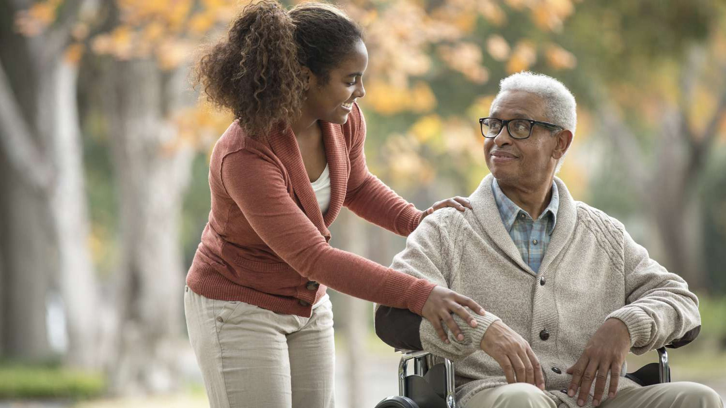 A person interacting with someone older who uses a wheelchair.