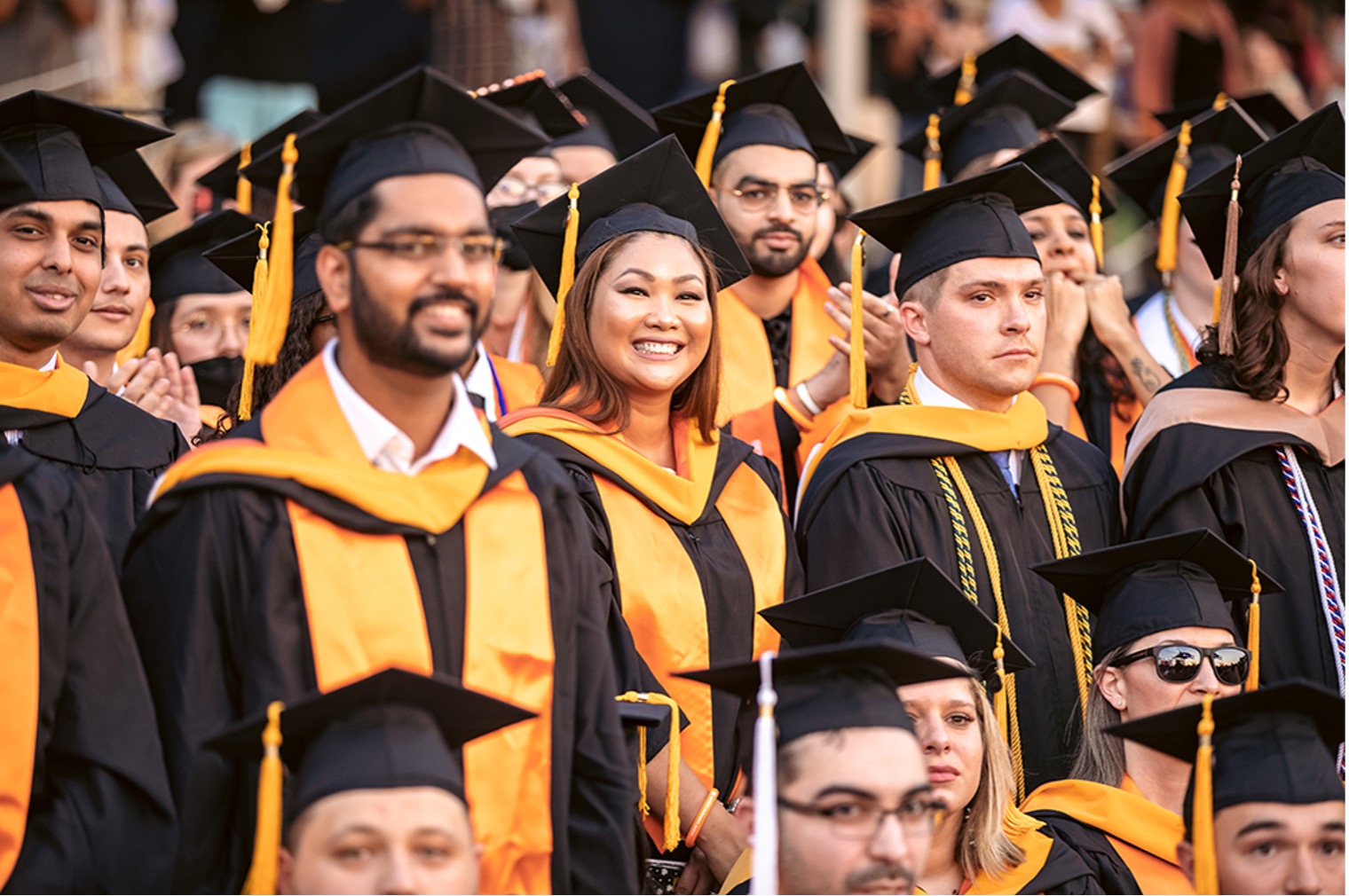Smiling graduates wearing regalia at University Commencement
