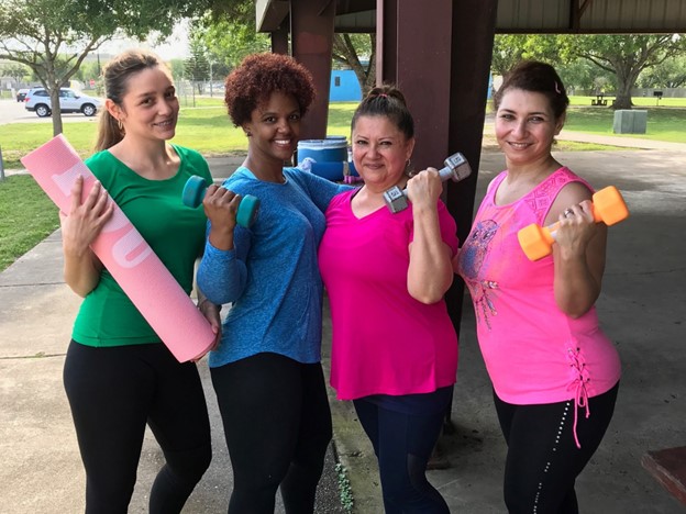 People in fitness clothing holding weights and yoga mats.