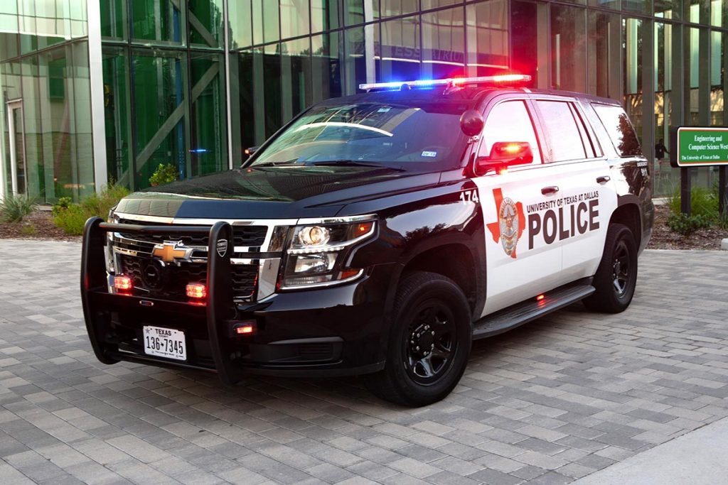 A police SUV with its lights on in front of the ECSW building.