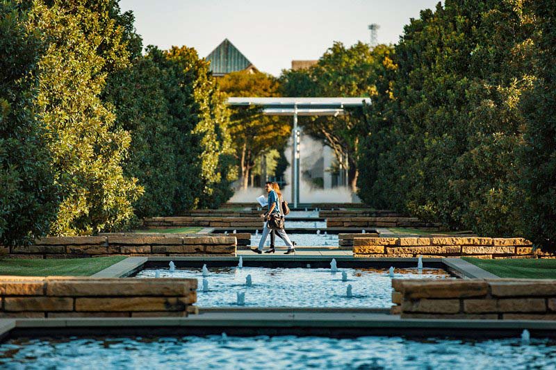 People walking past the reflecting pools and magnolia trees on campus. 