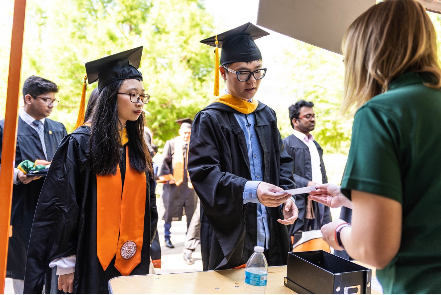 Graduating students hand their check-in information to a commencement volunteer.