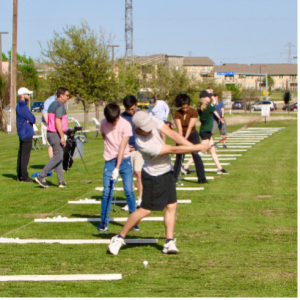 Golfers swinging clubs at the Golf Ranch driving range.